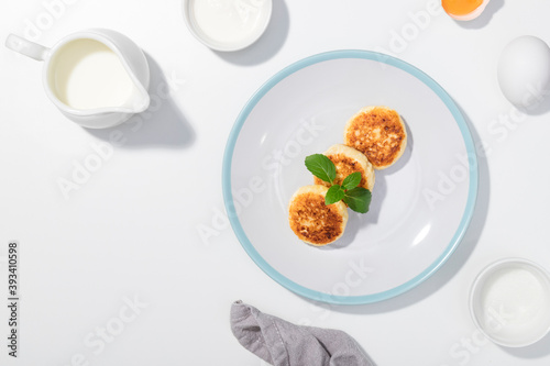 Cottage cheese, eggs, cream and yougurt on a white background - Flat lay with curd pancake - Recipe