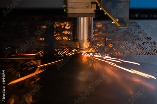 Automatic cnc laser cutting machine working with sheet metal with sparks at factory, plant. Metalworking, industrial, machining, technology, manufacturing, equipment concept