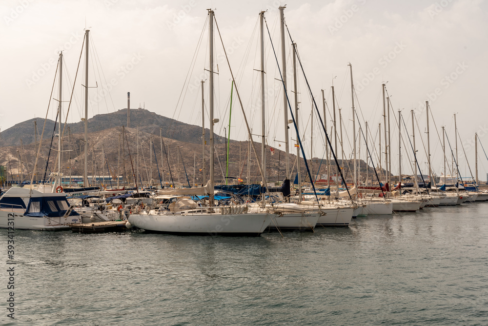 .row of boats moored in the harbor with mountains behind