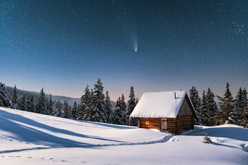 Fantastic winter landscape with wooden house in snowy mountains. Starry sky with comet and snow covered hut. Christmas holiday and winter vacations concept
