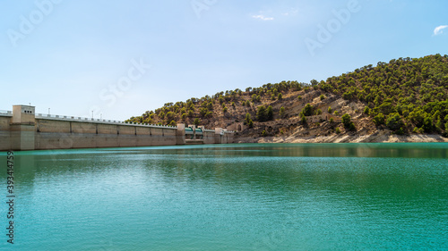 Landscape in which you can see the wall of the Amadorio reservoir in Villajoyosa with the turquoise water and the mountains with wild vegetation that surrounds it (Spain). Sunny summer day.