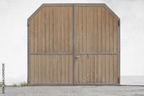 large wood barn door closed on a building, stone wall white and shutter blank with space for text
