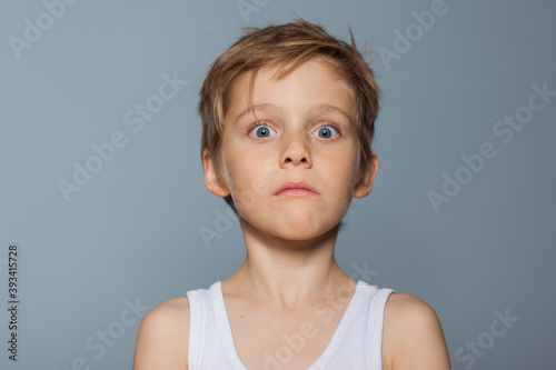 retrato de niño rubio con camiseta de tirantes y gesto muy expresivo de asombro photo