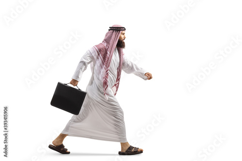 Full length profile shot of a saudi arab man with a briefcase running photo