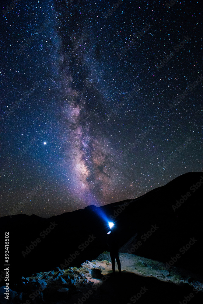 milky way over mountains with hiker and headlamp