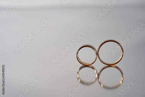 two gold wedding rings reflected on blurred gray background  