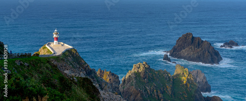 panorama of the Cabo Ortegal lighthouse in Galicia with green cliffs and sunlight and deep blue ocean