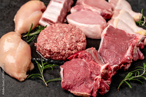 Various types of raw meat of beef, pork, chicken on a stone background