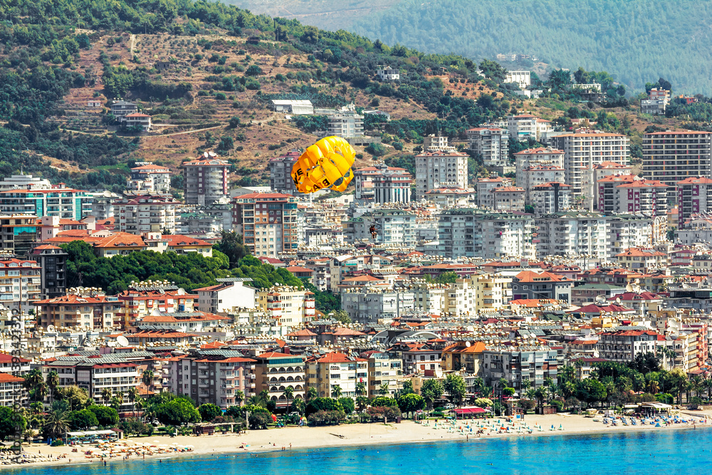 A parachute flies over the sea and beach in the background of Alanya in Turkey