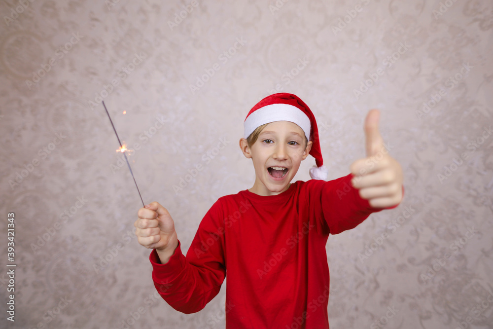 happy boy in Santa Claus hat with sparklers enjoys Christmas holidays happy boy in Santa Claus hat with sparklers enjoys Christmas holidays