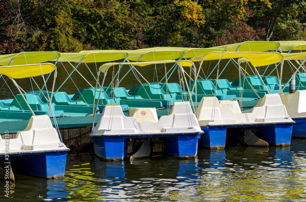 pedal boats with sun shelter in a row on a landing stage