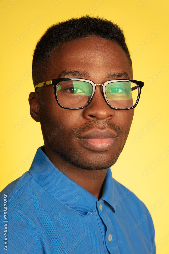 Wearing stylish eyewear. Young african-american man's portrait isolated on yellow studio background, facial expression. Beautiful male model, copyspace. Concept of human emotions, sales, ad. Wearing stylish eyewear. Young african-american man's portrait isolated on yellow studio background, facial expression. Beautiful male model, copyspace. Concept of human emotions, sales, ad.