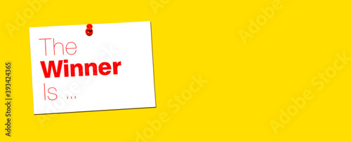White Note with the Words The Winner Is on a Yellow Wall