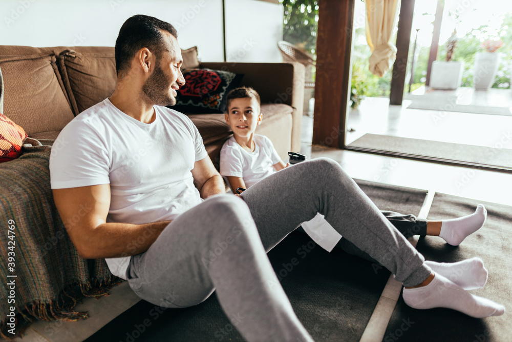 Latin father and son rest after exercising at home