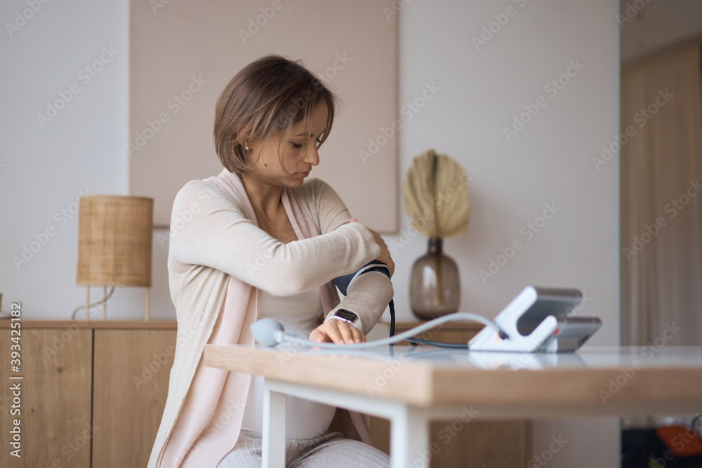 Pregnant woman measures blood pressure with an electronic tonometer. neuralgia during pregnancy, poor health. Hypertension. Severe pregnancy. Headache, migraine. High quality photo Pregnant woman measures blood pressure with an electronic tonometer. neuralgia during pregnancy, poor health. Hypertension. Severe pregnancy. Headache, migraine. High quality photo