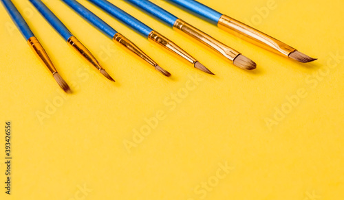 set of brushes on yellow.Set of blue brushes on a yellow paper background, close-up side view.