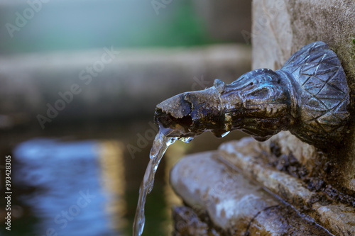 Agua fresa que sale del caño de una antigua fuente de parque