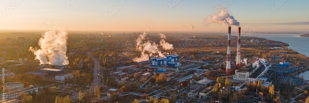 Aerial view. Emission to atmosphere from industrial pipes at sunrise. Smokestack pipes shooted with drone.