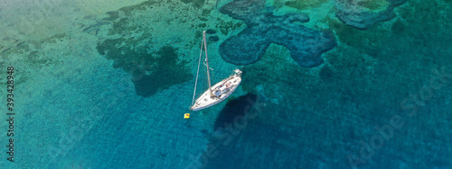 Aerial drone ultra wide photo of beautiful anchored sailboat in tropical exotic bay with emerald crystal clear sea