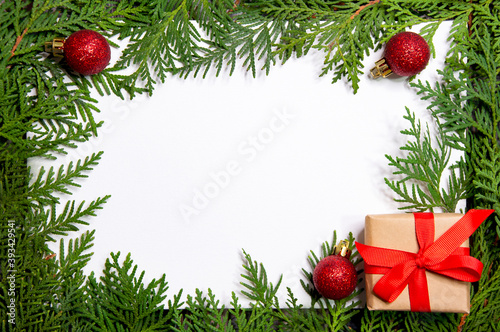 Thuja frame with new year red balls and gift on white background