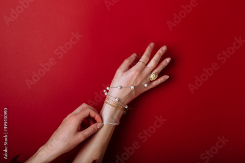 Fashion art hand woman in the glove protection against COVID-19 with Jewelry isolated on red background