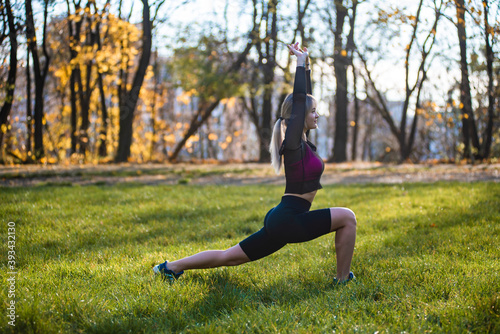 Portrait of fitness woman stretching her body in the park. Caucasian female working out in the morning.