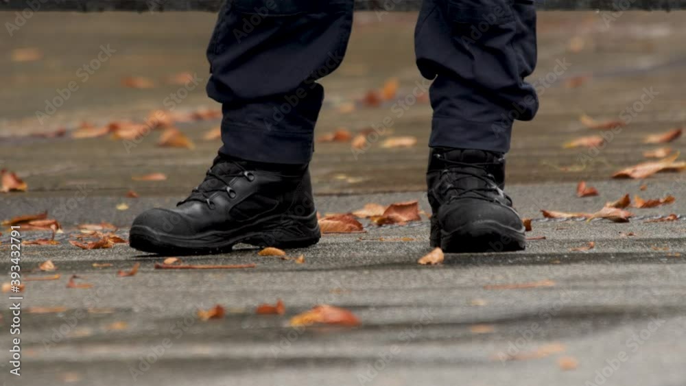 Autumn. Details. Military boots on the man's feet. Policeman's feet. Boots of Police officer in uniform. Legs of a policeman close up on duty. Feet of security guard in black boots. Fallen Leaves Autumn. Details. Military boots on the man's feet. Policeman's feet. Boots of Police officer in uniform. Legs of a policeman close up on duty. Feet of security guard in black boots. Fallen Leaves