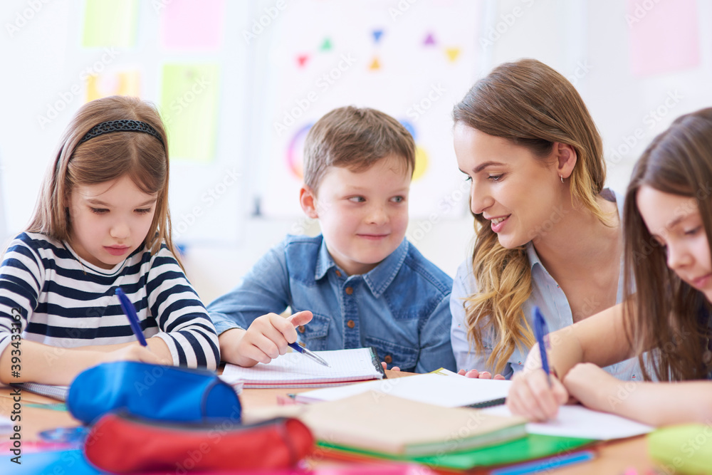Teacher helping pupils with their tasks in class Teacher helping pupils with their tasks in class