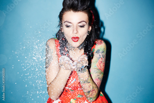 Tableau sur toile Portrait of tattooed woman blowing artificial snow