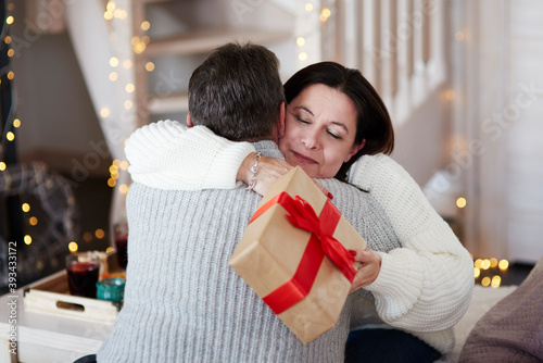 Wallpaper Mural Happy mature couple with gift box hugging in living room Torontodigital.ca