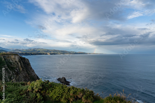 jagged and rocky ocean coast with cliffs and a rainbow © makasana photo