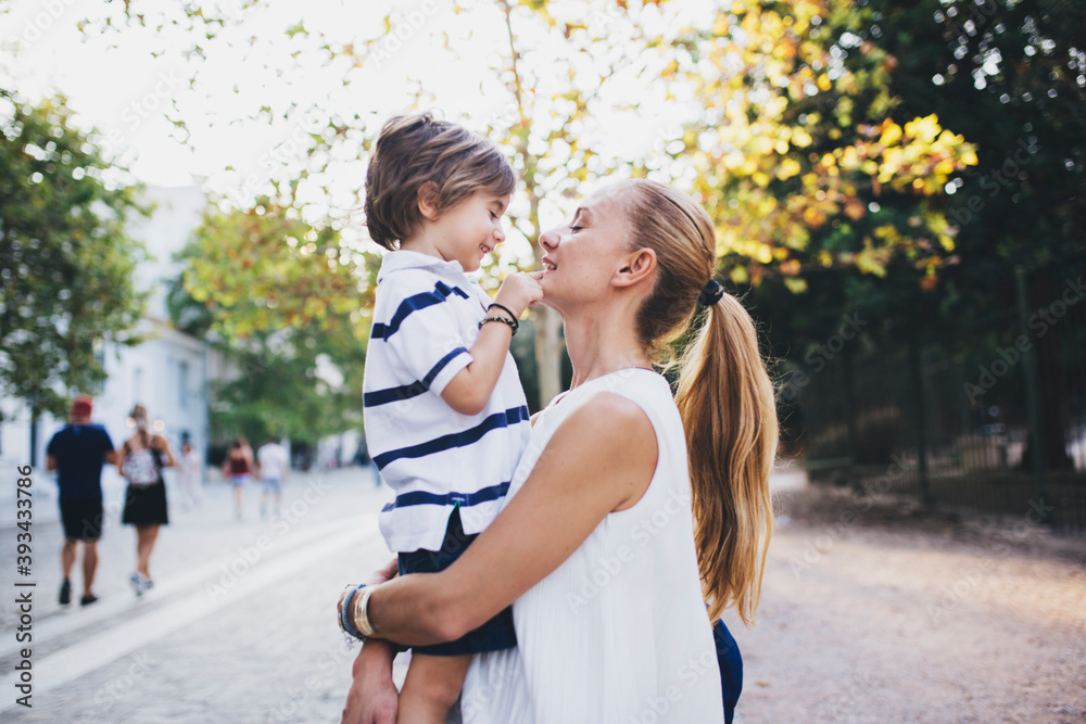 Mother standing in the city, holding her son Mother standing in the city, holding her son