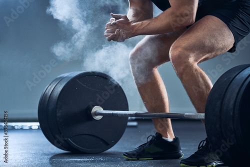 Close-up of man clapping hands before barbell workout at gym
