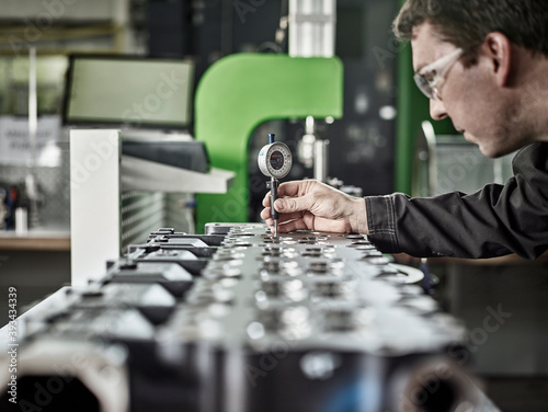 Worker in metalworking factory controlling cylinder head