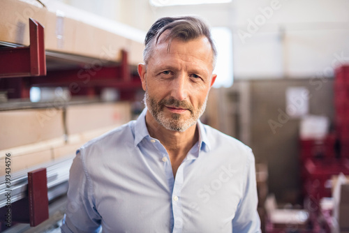Portrait of confident mature businessman in factory storeroom photo