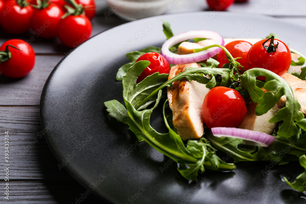 Delicious salad with chicken, vegetables and arugula on grey table, closeup