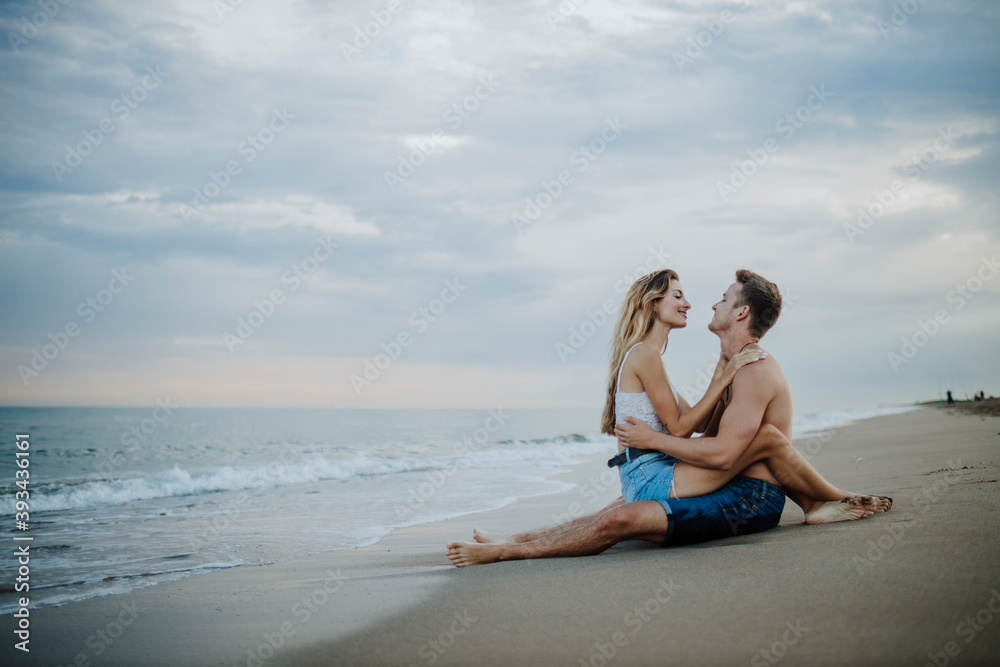 Young couple looking at each other while sitting on beach Young couple looking at each other while sitting on beach