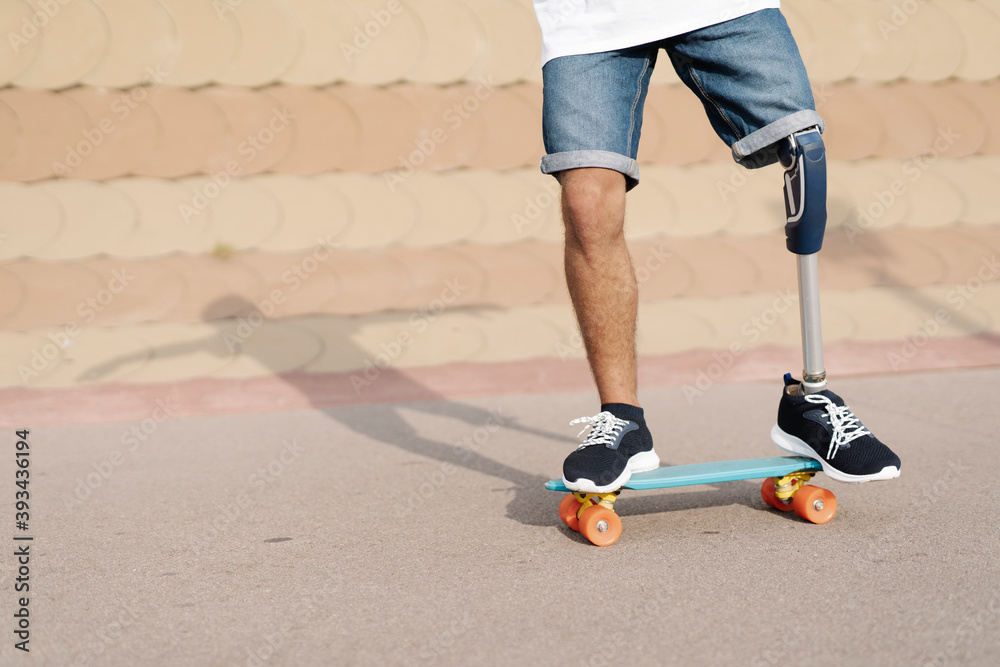 © joan corominas/Westend61 - Young man with physical disability standing on skateboard at sports court