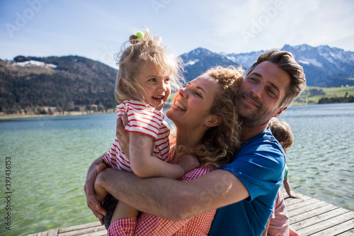 Austria, Tyrol, Walchsee, happy family hugging on a jetty at the lakeside