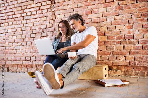 Businessman and woman sitting in a loft, using laptop, founding a start-up company