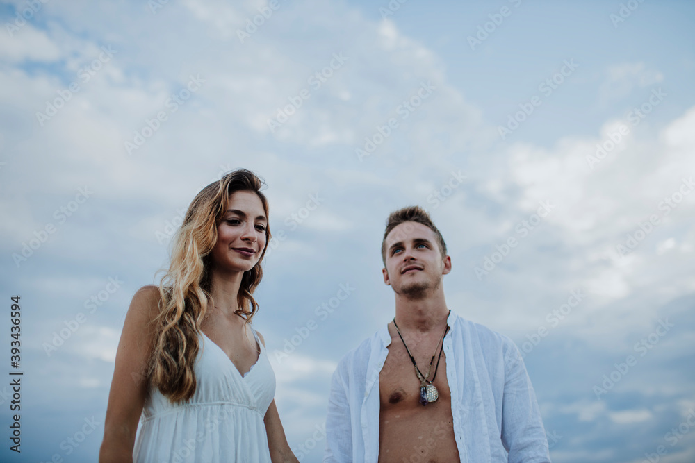 Smiling man and woman looking away while standing against sky Smiling man and woman looking away while standing against sky