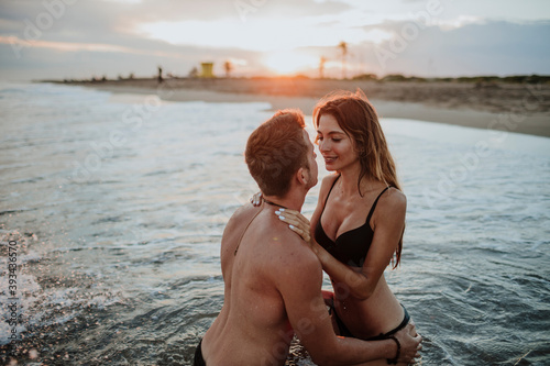 Couple wearing swimwear doing romance in water at beach