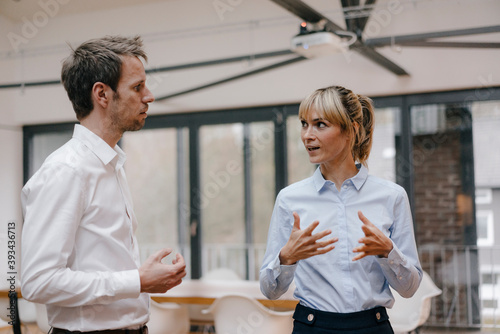 Businessman and woman standing in office, discussing