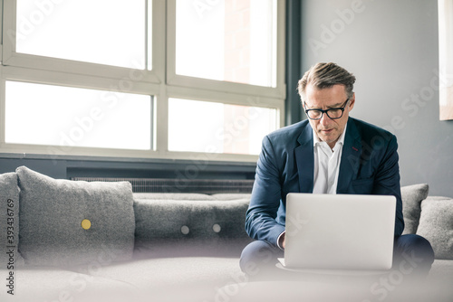 Mature businessman using laptop on couch photo