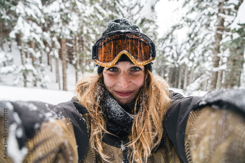 Portrait of smiling young woman in skiwear in winter forest