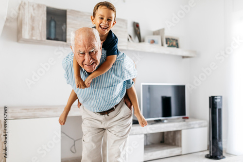 Portrait of grandfather giving his grandson a piggyback ride in the living room photo