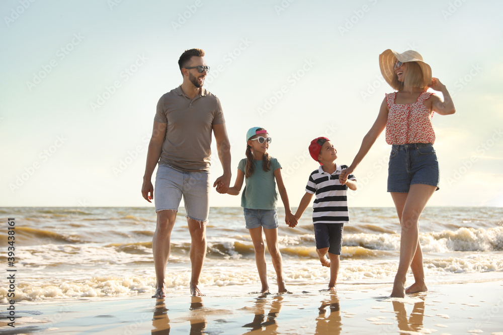 Happy family walking on sandy beach near sea