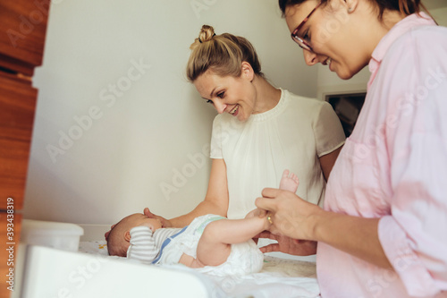 Midwife showing mother how to change diapers of newborn baby