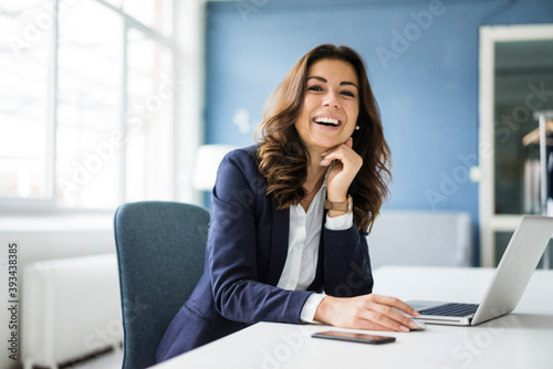 Portrait of laughing businesswoman sitting at desk in the office photo