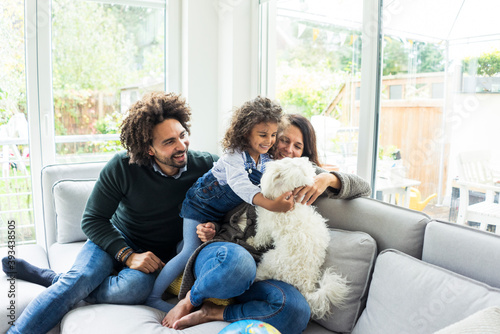 Happy family with dog sitting together in cozy living room
